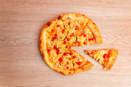 Pizza with one slice missing on wooden table, top view, showing melted cheese and tomato sauce, perfect for food promotion and delivery designの写真素材