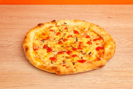 Hot pizza with tomato sauce and melted cheese on wooden table, blurred background bottles of olive oilの写真素材