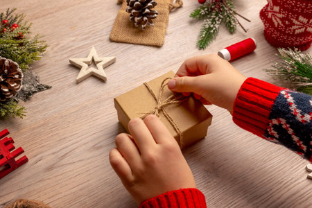 Child opening a small Christmas gift surrounded by festive decorations, creating a warm family holiday moment perfect for seasonal storytelling and emotional campaigns.の写真素材
