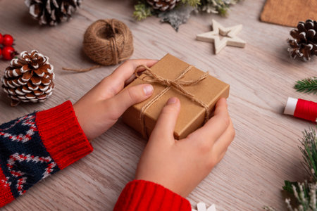 Child holding a small wrapped Christmas gift, capturing anticipation and joy perfect for emotional holiday campaigns and family themed promotionsの写真素材