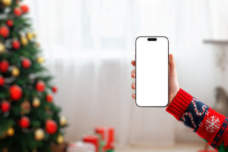 Blank phone screen mockup in a cozy Christmas setting, ideal for holiday designs, mobile apps, seasonal promotions and festive marketing visualsの写真素材