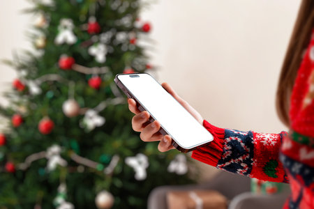 Stylish Christmas phone mockup with blank screen and festive tree background, ideal for winter campaigns, app presentations, holiday graphics and marketing visualsの写真素材