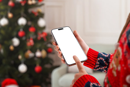 Christmas-themed phone mockup with hand tapping the screen, perfect for mobile app previews, winter marketing, festive designs and holiday promotionsの写真素材