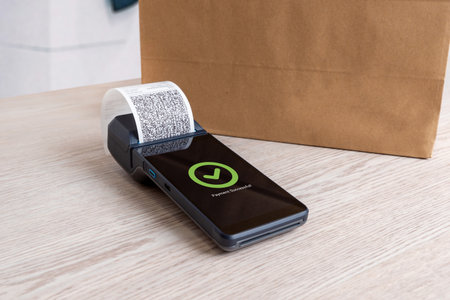 POS terminal on wooden desk showing payment successful message with printed receipt, representing modern digital retail transactionの写真素材