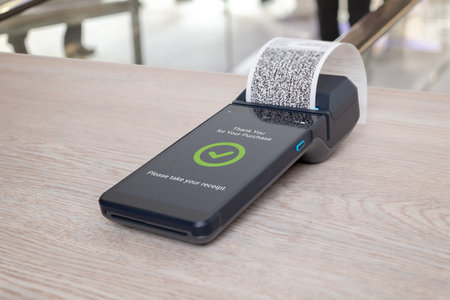 OS terminal with printed receipt and thank you message displayed on screen, illustrating completed retail payment processの写真素材