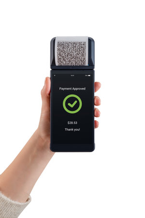 Hand holding POS terminal with printed receipt and payment approved message, showing completed digital transaction and modern retail technologyの写真素材