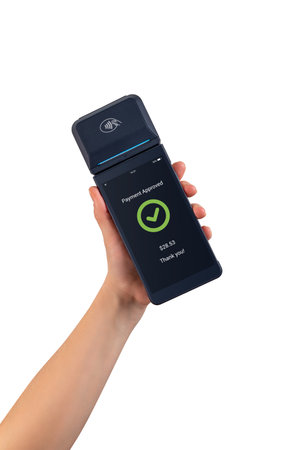 Hand holding wireless POS terminal displaying payment approved screen, showing modern digital checkout and cashless transaction technology on white backgroundの写真素材