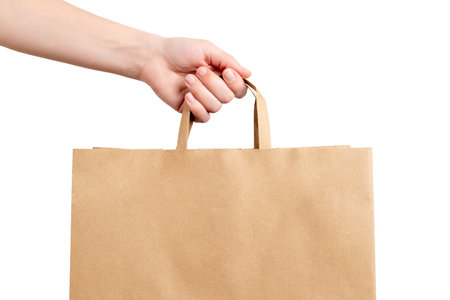 Hand holding kraft paper shopping bag on white background, showing eco packaging and retail purchase concept in a clean minimal styleの写真素材