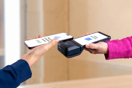 Contactless payment interaction with smartphone and POS terminal, showcasing modern tap-to-pay technology and seamless NFC transaction between customer and merchantの写真素材