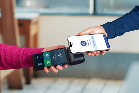 Smartphone initiates a contactless payment near a POS terminal, showing a mobile wallet app ready for NFC tap-to-pay inside a modern cafÃ© environmentの写真素材