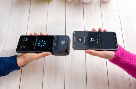Smartphone and POS terminal performing an NFC payment, showing a processing screen during a seamless tap-to-pay transaction in a clean retail environmentの写真素材