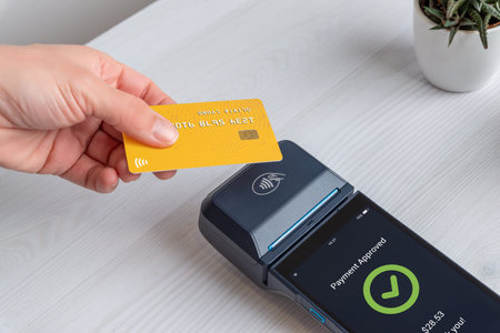 Contactless credit card payment approved on modern POS terminal at retail checkout, showing...