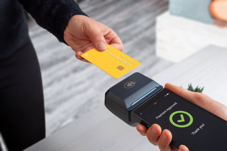Contactless credit card payment using mobile POS terminal and smartphone in retail store, showing...