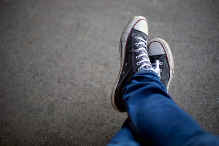 Top view of legs in jeans and sneakers on asphalt