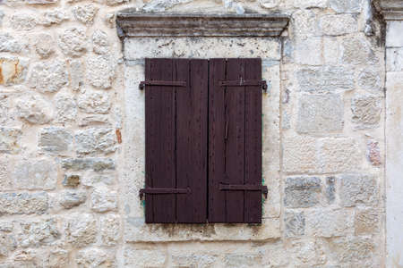 Closed brown wooden window shutters on an beautiful old stone seaside house.の写真素材