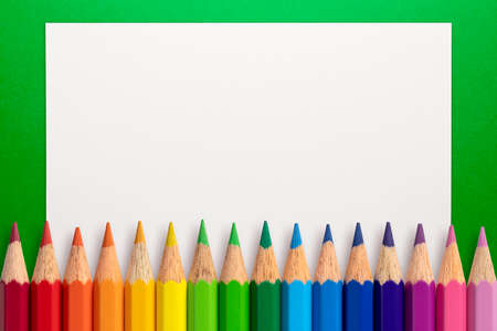 Frame made of color pencils and white paper on an green background.の写真素材
