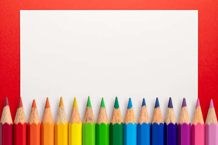 Frame made of color pencils and white paper on an red background.の写真素材