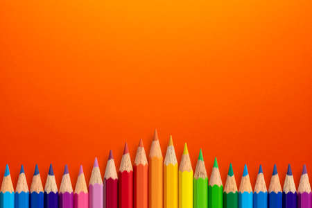 Creative background made of colour pencils on orange paper. Flat lay. Education concept.の写真素材