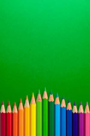 Creative vertical background made of colour pencils on green paper. Flat lay. Education concept.の写真素材