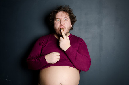 Funny overweight man eating chocolateの写真素材