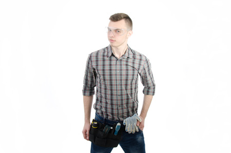 Young handsome handyman. White background. A handsome man in studio. Tools and businesslike. Serious and with a smile.の写真素材