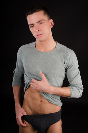 Young sexy man with a beautiful body. Model with athletic body posing on a black background. Young attractive guy.の写真素材