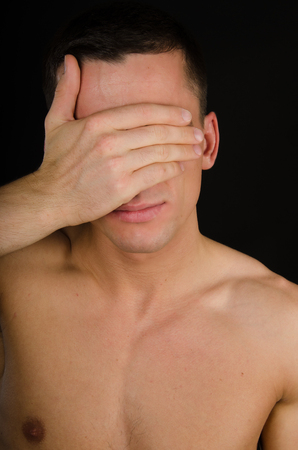 Young handsome guy covering his face with his hands. Handsome man closes his eyes with his hand. See no evil.の写真素材