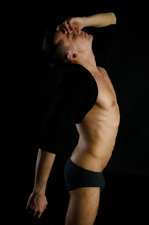 Young sexy man with a beautiful body. Model with athletic body posing on a black background. Young attractive guy.の写真素材