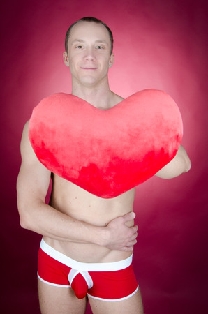 Love and happiness. Attractive man shirtless. Young sexy man holding toy heart. Romance and passion. Love and tenderness.の写真素材
