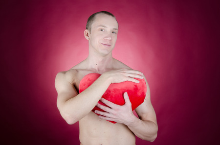 Love and happiness. Attractive man shirtless. Young sexy man holding toy heart. Romance and passion. Love and tenderness.の写真素材