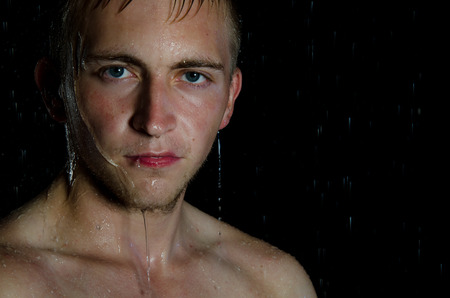Young handsome guy in shower. Water, cleanliness and freshness. Young sexy guy in shower. Handsome and attractiveの写真素材