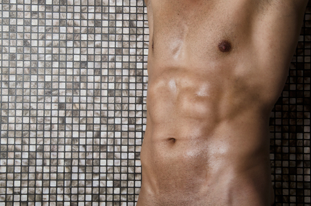 Shower. Sexy naked man washes. Clean and hygiene. Guy with an athletic body wash in the shower.の写真素材