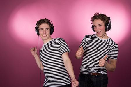 Two attractive guys listening to headphones.