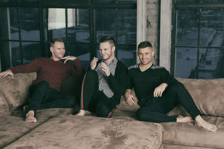 Three attractive guys relaxing at home.の写真素材
