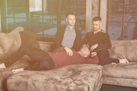 Three attractive guys relaxing at home.の写真素材