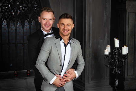 Young happy gay couple getting married in church. Love and romance. Handsome men in suits.の写真素材