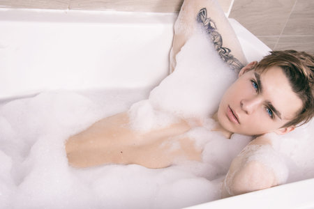 Attractive man in the bath with foam.