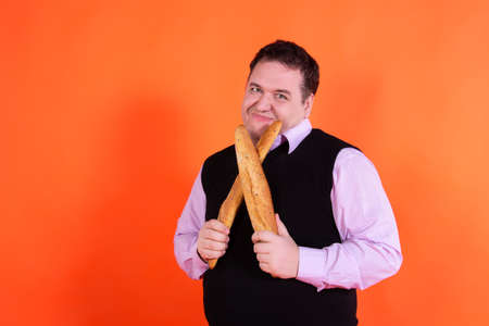 Funny fat guy on a diet. Happy man with baguettes.の写真素材