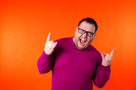 Relaxed funny thick man, dances while listens music, moves arms and closes eyes in enjoyment, wears headphones on ears, has fun and feels aspiration.の写真素材