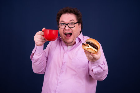 Sport, fitness and healthy lifestyle. Funny fat guy goes in for sports and eats a hamburger.の写真素材