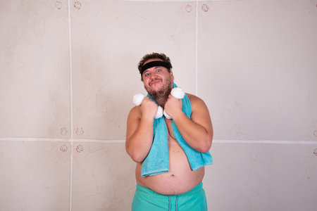 Funny fat man goes in for sports at home.の写真素材