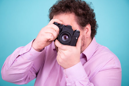 Portrait of a man with a camera on a turquoise backgroundの写真素材