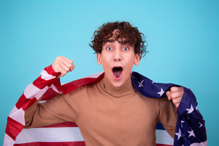 Portrait of a young man with American flag on blue backgroundの写真素材