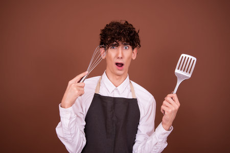 Portrait of a young handsome man wearing apron against brown background