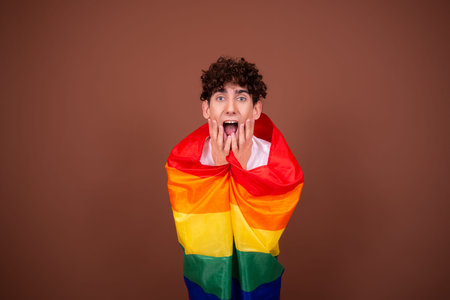 Portrait of a young man covering his mouth with a rainbow flag