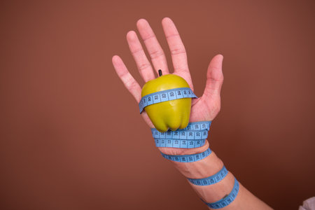 Healthy lifestyle concept. Female hand with measuring tape around apple.の写真素材