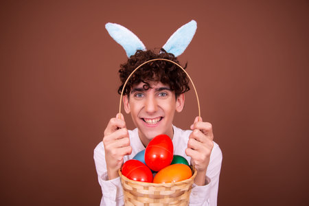 Studio shot of young handsome man against brown background with easter bunny ears