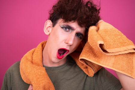 Young man with a towel on his head on a pink background.