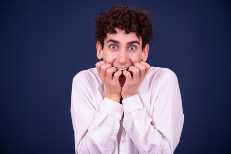 Portrait of a young man with curly hair standing against blue backgroundの写真素材