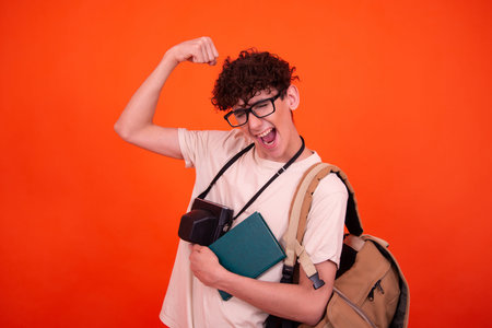Portrait of young male student with backpack and books on red background